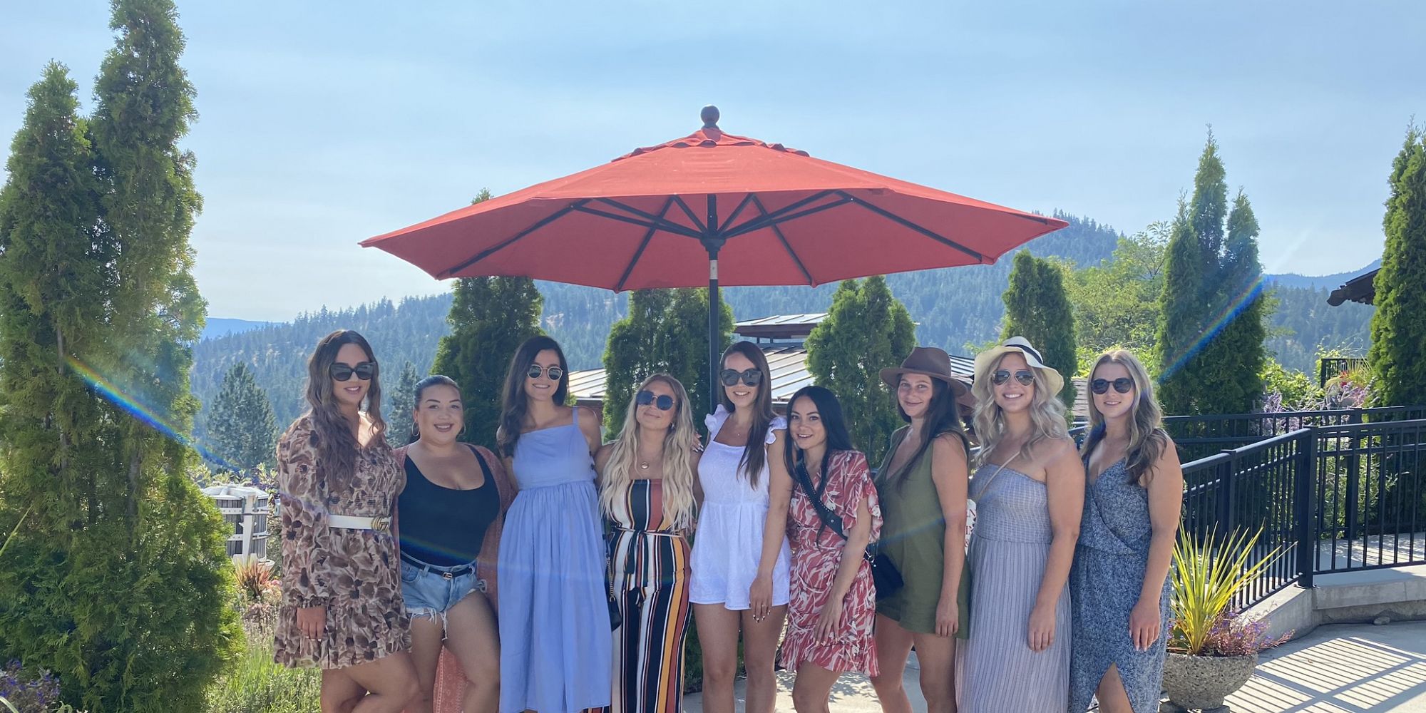 Nine Ladies Standing Under A Big Red Umbrella On Dirty Laundry Vineyards Patio