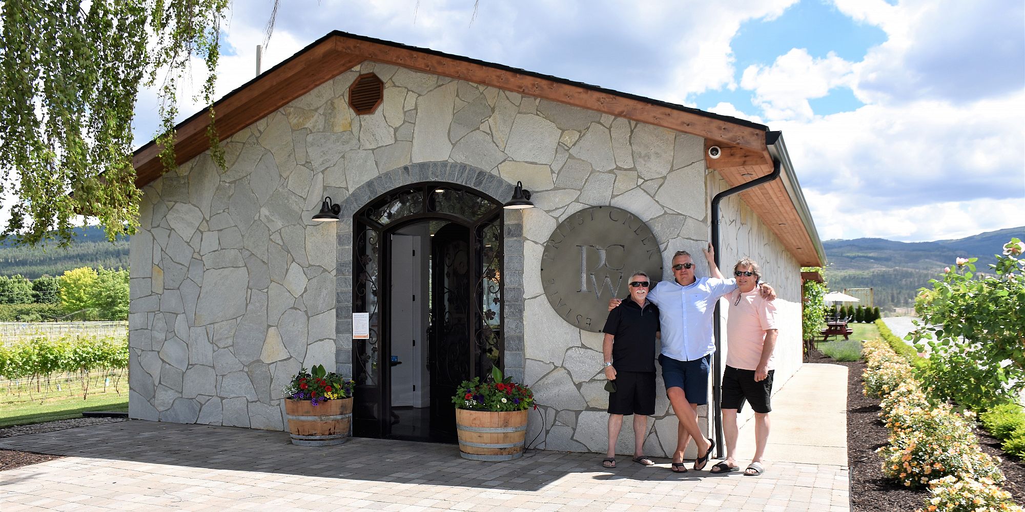 Three Male Friends Smiling In Front Of The Wineshop At Priest Creek Estate Winery