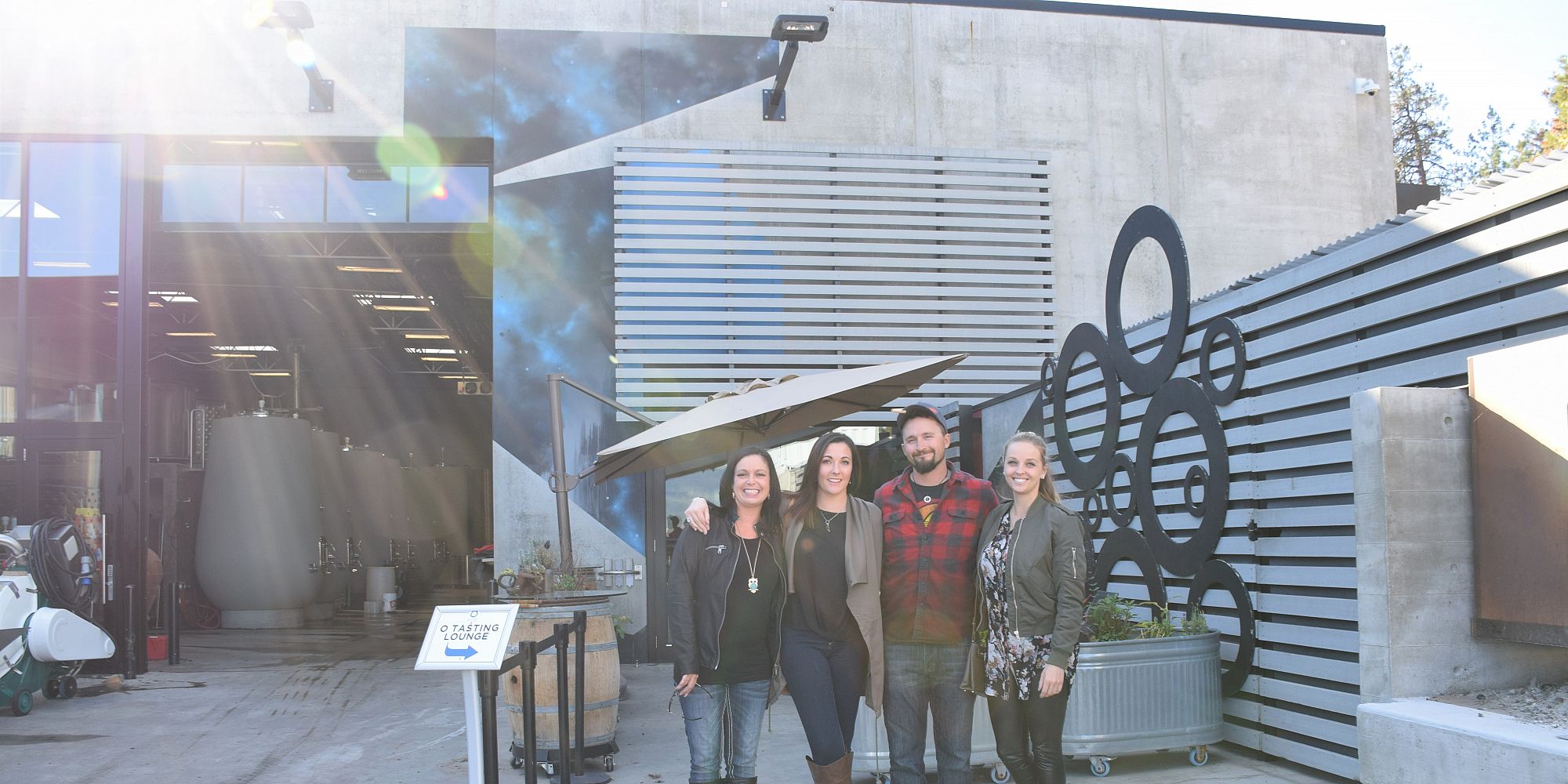 Four Friends On The Crush Pad Surrounded By Wine Making Equipment At Haywire Winery